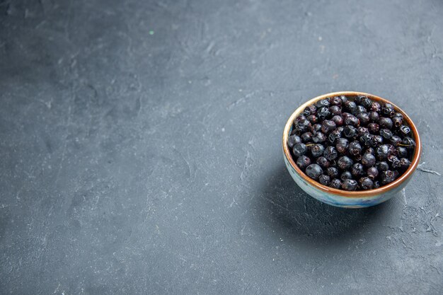 Bottom view black currant in bowl on dark surface with copy space