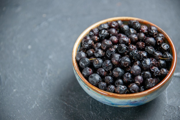 Bottom view black currant in bowl on dark surface with free place