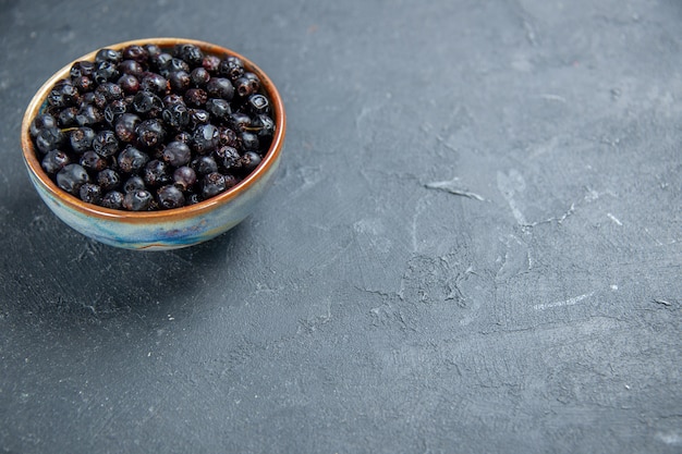 Bottom view black currant in bowl on dark surface with free place