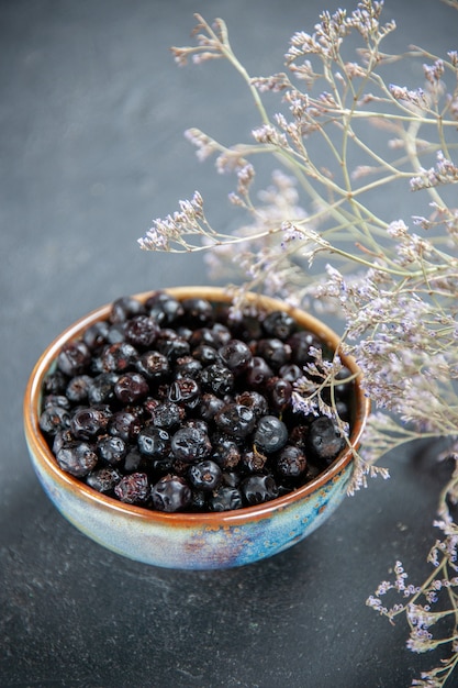 Bottom view black currant in bowl dried flowers on isolated surface