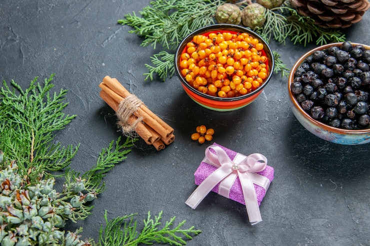Free Photo bottom view black currant sea buckthorn in bowls pine branches pinecones on dark surface