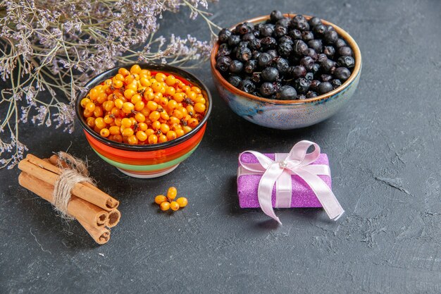 Bottom view black currant sea buckthorn in bowls small gift on dark surface