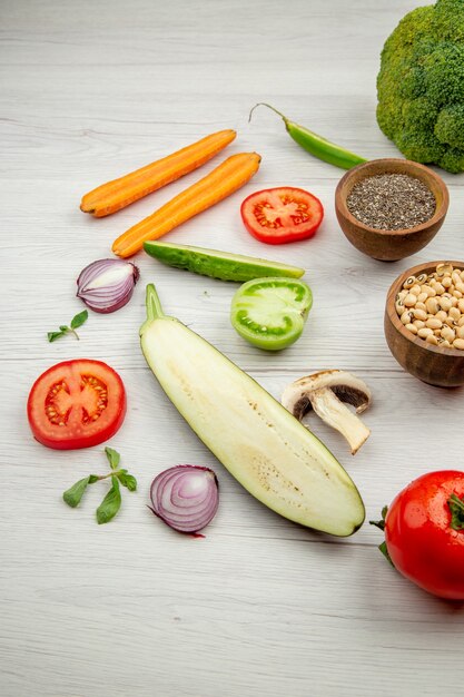 Bottom view black-eyed peas and black pepper in small bowls cut vegetables on white table