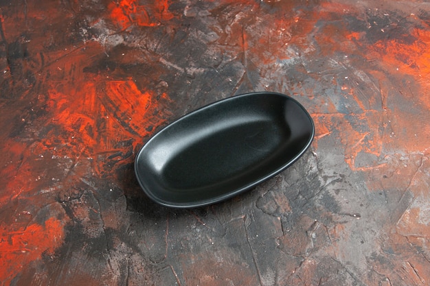 Вид снизу черная овальная тарелка на темно-красном пространстве для копирования стола