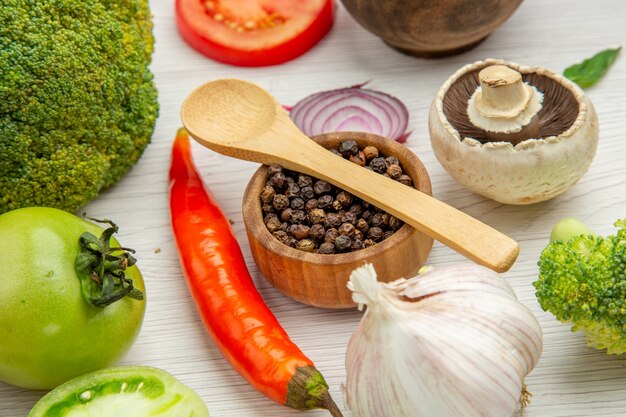 Bottom view black pepper broccoli garlic wooden spoons on spice bowl mushroom on grey table