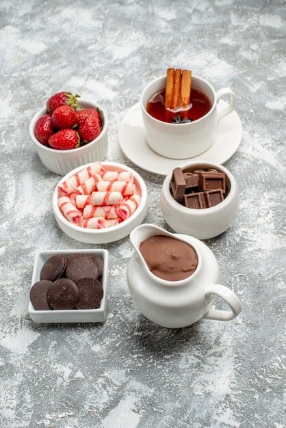 Bottom view bowls with cacao candies strawberries chocolates tea with cinnamon and anise seed on the grey-white table