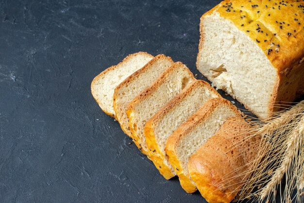 Вид снизу ломтики хлеба колосья пшеницы на темном столе со свободным пространством