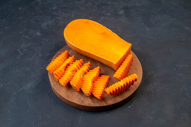 Bottom view butternut squash chopped with zig-zag knife on wood board on table