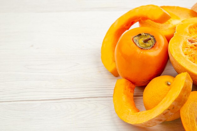 Bottom view butternut squash mandarin persimmons on white table with free space