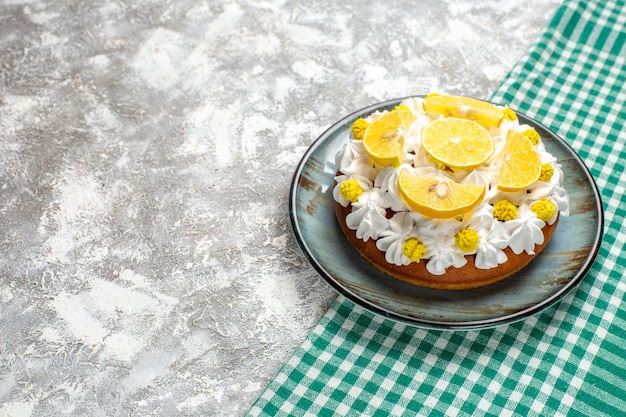 Bottom view cake with white pastry cream and lemon slices on round plate on green and white checkered table