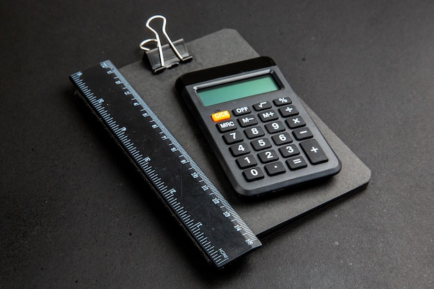 Bottom view calculator and ruler on notepad on dark table