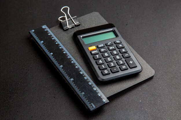 Bottom view calculator and ruler on notepad on dark table