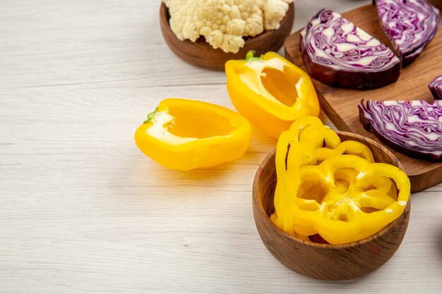 Bottom view chopped bell peppers in bowls cut red cabbage on cutting board on white surface free space