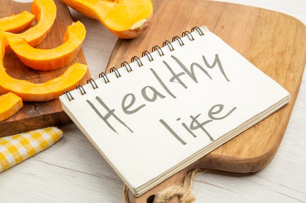 Bottom view chopped butternut squash on chopping board healthy life written on notepad on cutting board on grey table
