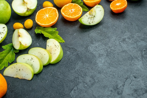 Vista dal basso frutta tritata arance mele cumcuat con polvere di menta su spazio libero terreno scuro