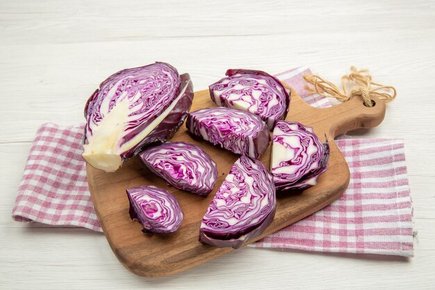 Bottom view chopped red cabbage on cutting board on pink and white checkered kitchen towel on grey table