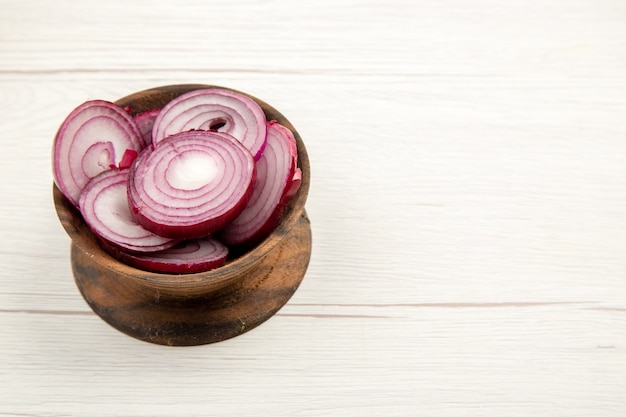 Free photo bottom view chopped red onion in wooden bowl on white table with free space