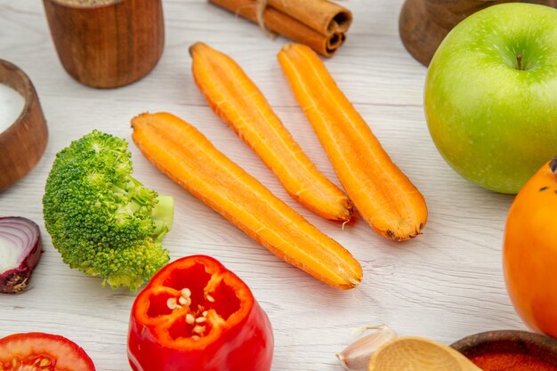 Bottom view chopped vegetables carrot broccoli bell pepper apple small bowls on grey wooden table