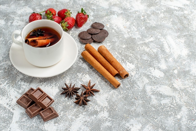 Vista dal basso tè alla cannella ai semi di anice e alcune fragole cioccolatini cannellini semi di anice sul lato sinistro del tavolo