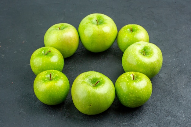 Круглый ряд снизу зеленые яблоки на темной поверхности