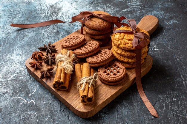 Bottom view cookies and biscuits anises cinnamon sticks on wood serving board on dark background
