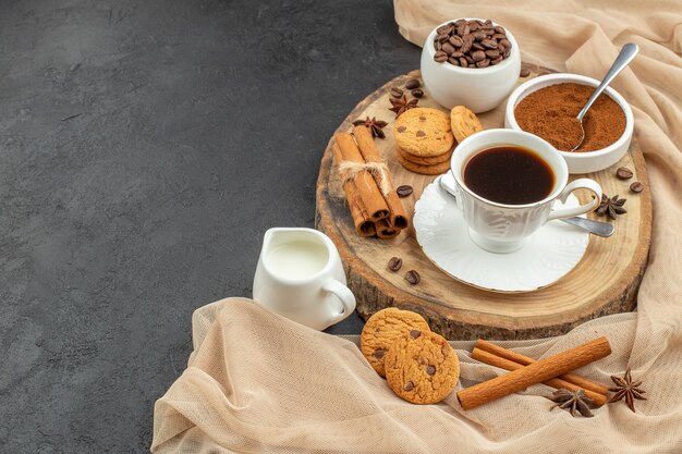 Bottom view cup of coffee cookies cinnamon sticks milk cup wood board on dark 
