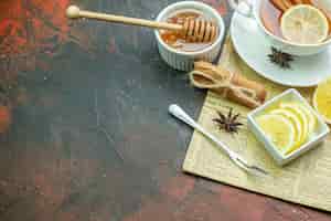 無料写真 小さなボウルフォークシナモンスティックのティーレモンスライスの底面図アニス蜂蜜とコピー場所のある濃い赤のテーブルの新聞のメモ帳のボウルの蜂蜜スティック