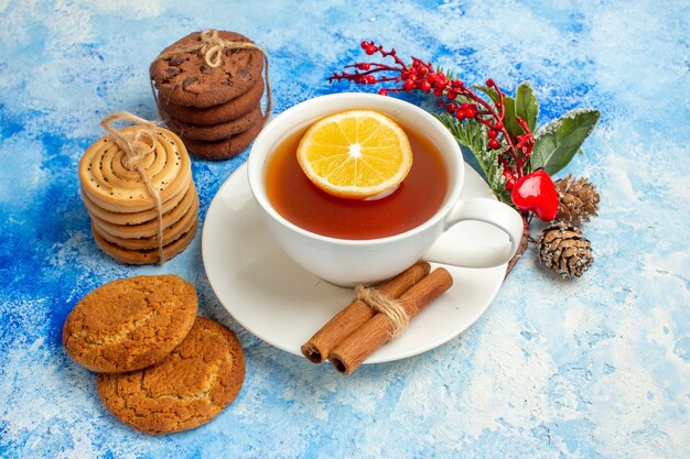 Bottom view cup of tea flavored by lemon and cinnamon cookies tied up with rope on blue table