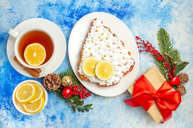 Vista dal basso una tazza di tè con fette di limone torta sul piatto regalo di natale sul tavolo blu