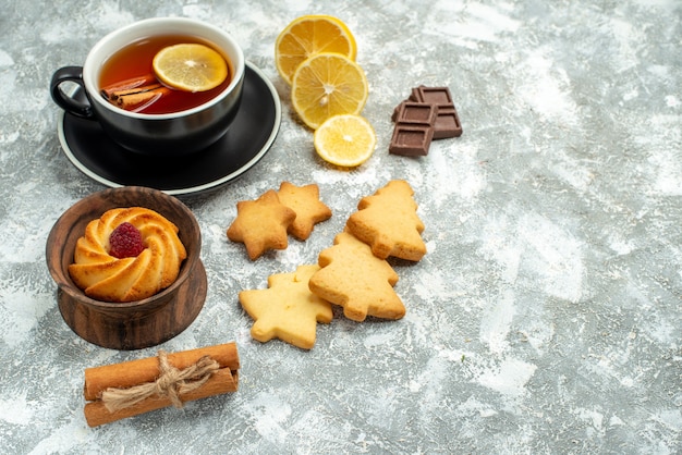 Bottom view a cup of tea lemon slices cinnamon sticks cookies chocolate on grey surface free space