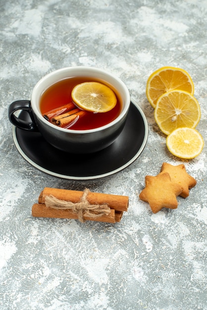 Foto gratuita vista dal basso una tazza di tè fette di limone bastoncini di cannella su superficie grigia