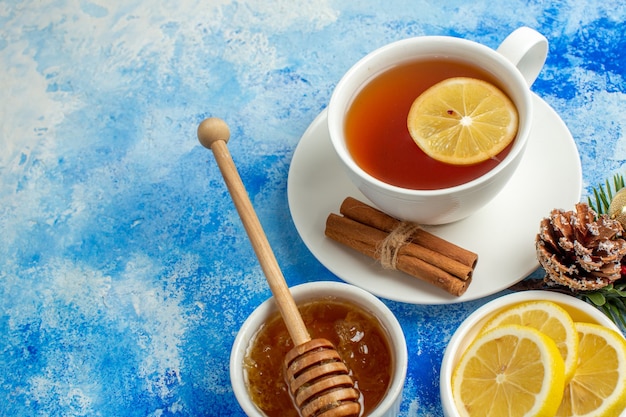 Bottom view cup of tea lemon slices honey in bowl on blue table free space