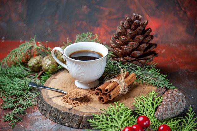 Bottom view a cup of tea on wood board cinnamon sticks pinecone pine tree branches on dark