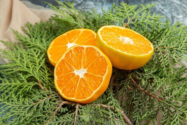 Bottom view cut oranges on pine branches on dark surface