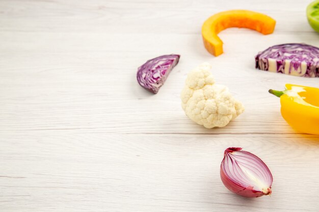 Bottom view cut vegetables red cabbage green tomato pumpkin yellow bell pepper caulifower on white wooden surface free space