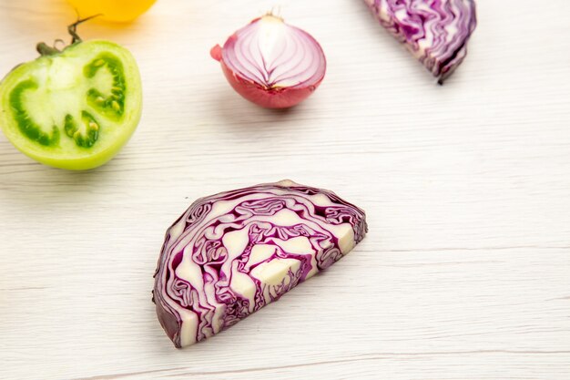 Bottom view cut vegetables red cabbage green tomato red onion on white wooden surface