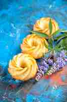 Foto gratuita biscotti di fila diagonale vista dal basso ramo di fiori viola sul tavolo rosso blu