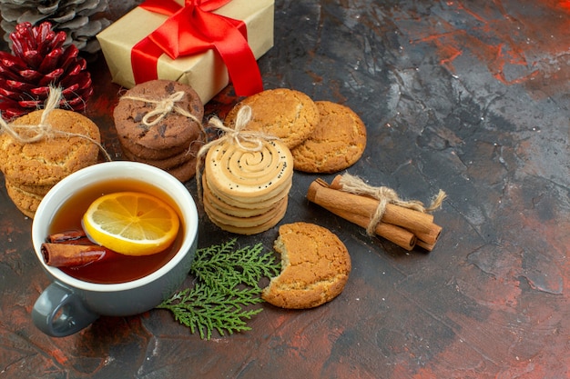 Bottom view different cookies tied with rope cup of tea pinecones gift on dark red table