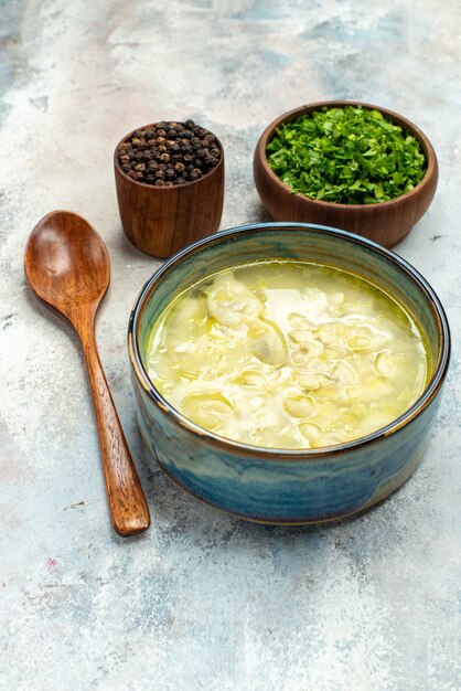 Bottom view dushbara dumplings soup bowls with greens pepper wooden spoon on nude background