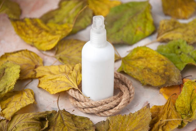 Bottom view empty spray bottle around fall leaves rope on nude background