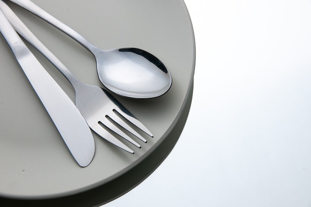 Bottom view fork spoon knife on plate on white isolated surface copy place