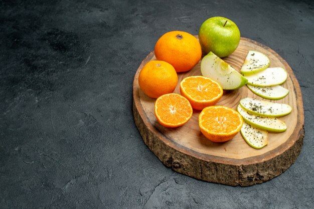 底面図新鮮なリンゴとオレンジ、乾燥したミントパウダー、空きスペースのある黒いテーブルの上の木の板