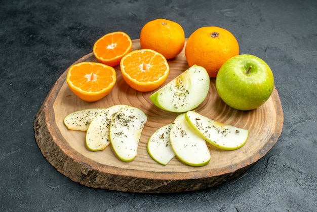 Vista dal basso mele e arance fresche tagliate con polvere di menta secca su tavola di legno su tavola nera