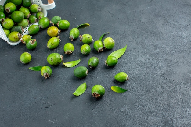 Free photo bottom view fresh feijoas scattered from plastic basket on dark surface with copy space