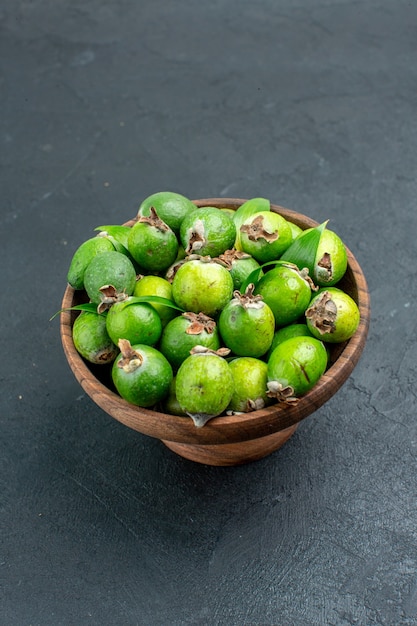 Foto gratuita feijoas freschi di vista dal basso in ciotola di legno su superficie scura