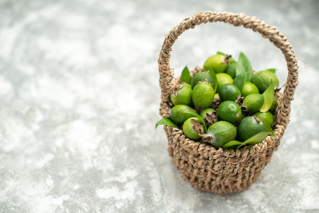 Bottom view fresh feykhoas in wicker basket on grey isolated surface with copy place