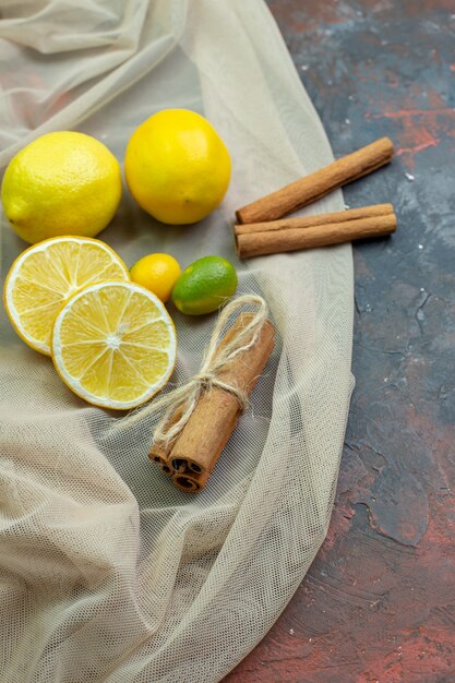 Bottom view fresh lemons cut lemons cumcuats cinnamon sticks oon tulle on dark red ground