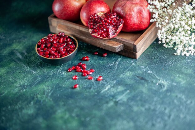 Bottom view fresh pomegranates on wood serving board flowers on table free space