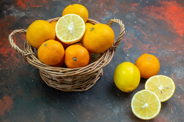 Bottom view fresh tangerines in wicker basket fresh lemons on dark table