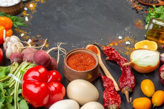 Bottom view fresh vegetables red pepper powder in small bowl and wooden spoon oil bottle on table copy place